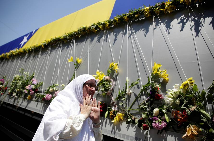 A woman reacts near a truck carrying coffins of newly identified victims of the 1995 Srebrenica massacre, in front of the presidential building in Sarajevo