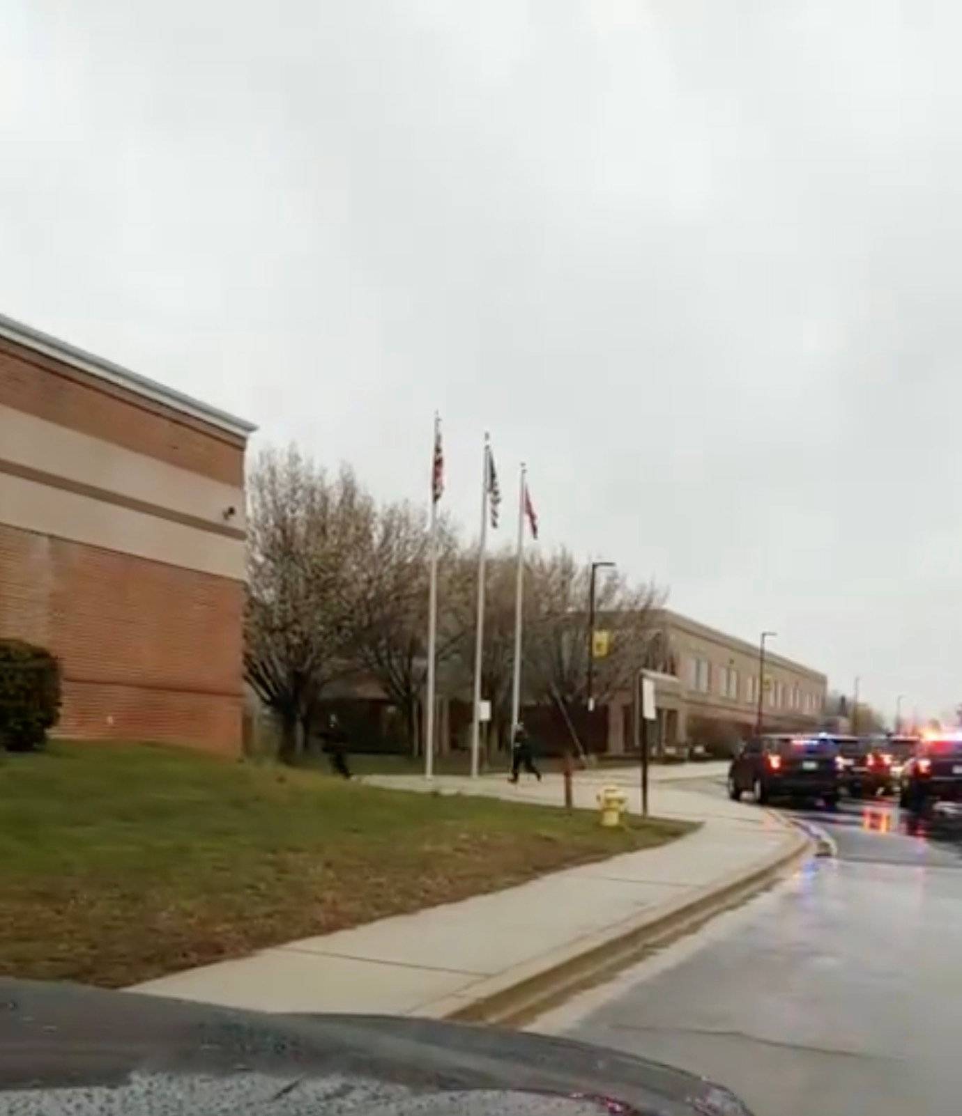 Law enforcement officers run towards Great Mills High School in Lexington Park