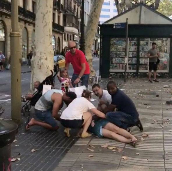 People help an injured woman after a van crashed into pedestrians near the Las Ramblas avenue in central Barcelona