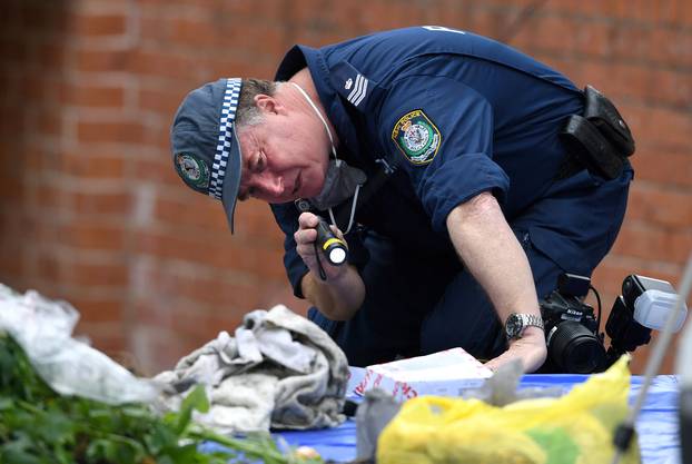 An Australian police officer searches items seized from a property during a raid in the Sydney suburb of Lakemba