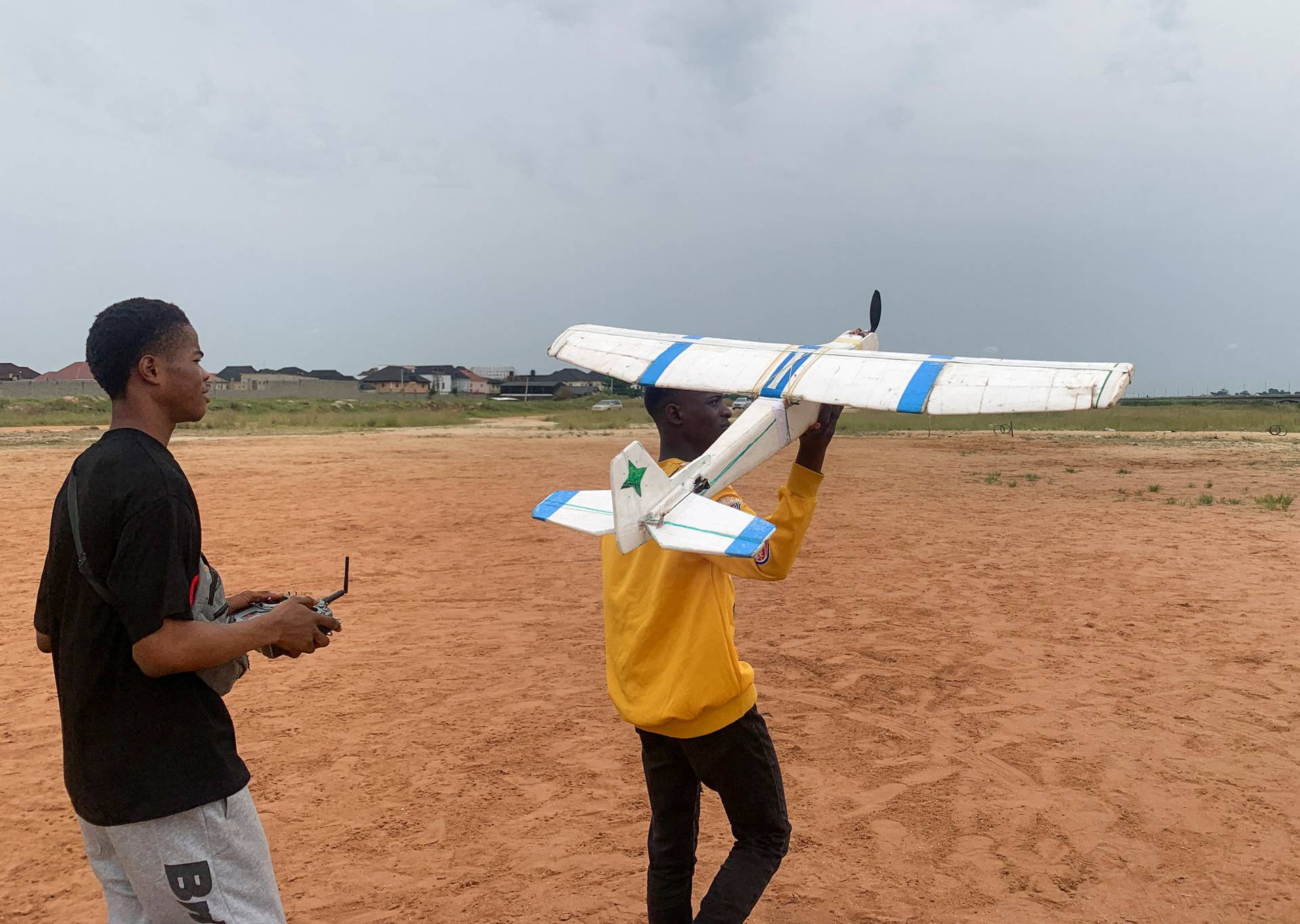 Chris Chinedu and Damilare Ajayi, friends of Bolaji Fatai, who built the model aeroplane from discarded waste, prepare to fly the model aeroplane, in Lagos