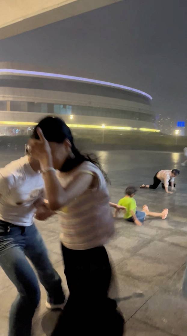 People seek shelter from wind near Zhuhai Opera house building, during typhoon Wipha, in Zhuhai