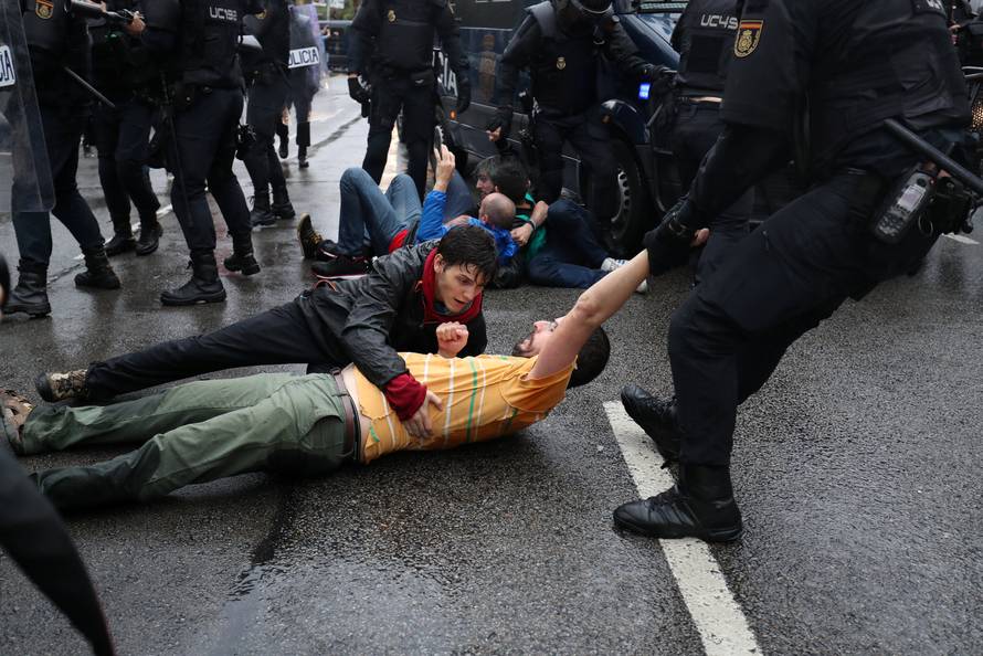 Riot police remove demonstrators outside a polling station for the banned independence referendum in Barcelona