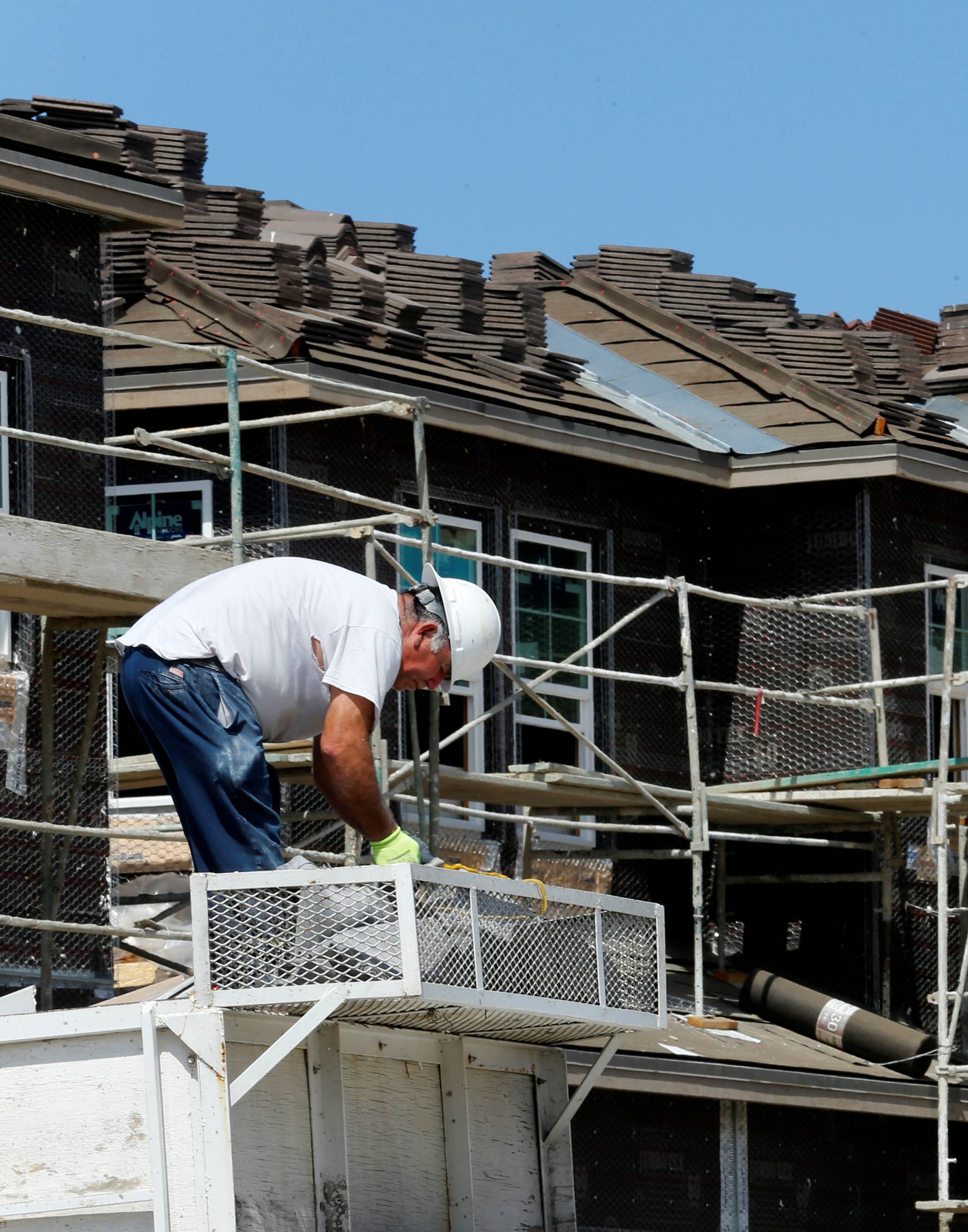 A construction worker is shown building luxury single family homes in Carlsbad, California