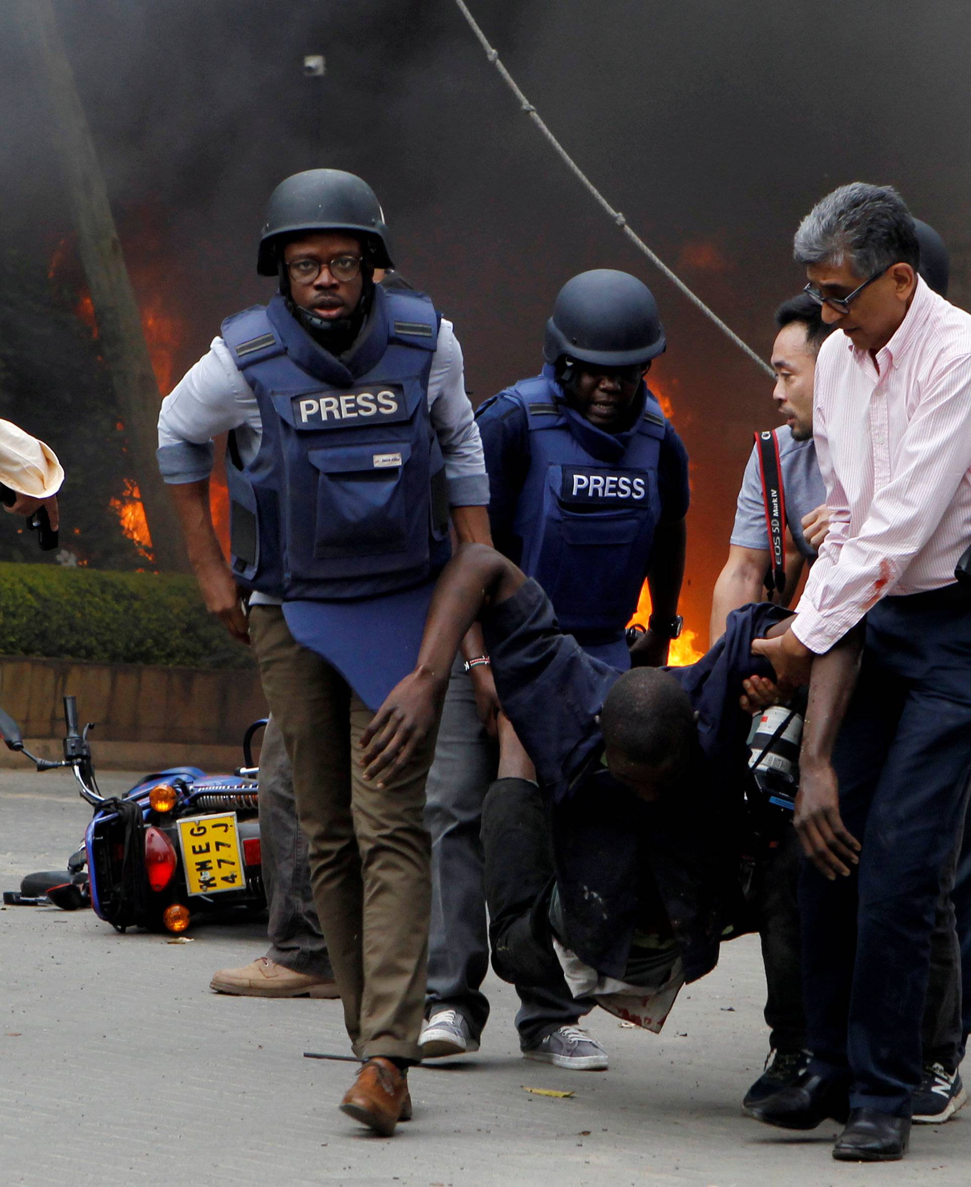 Rescuers and journalists evacuate an injured man from the scene where explosions and gunshots were heard at the Dusit hotel compound, in Nairobi