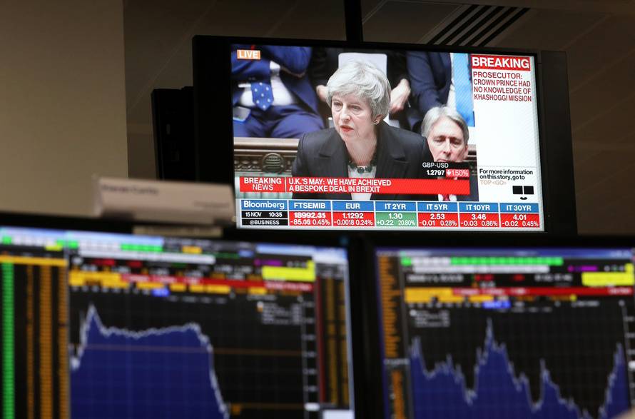 An investment manager's desk, in the office of Aberdeen Standard Investments, is seen below a televison showing Britain's Prime Minister, Theresa May, delivering a statement to the House of Commons, in London