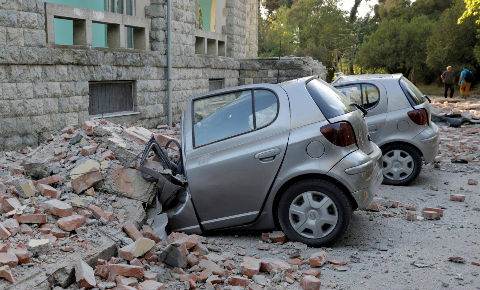 Destroyed cars stand next to a damaged building after an earthquake in Tirana