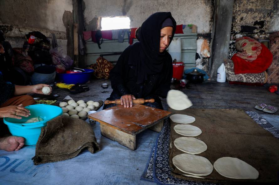 The sister of displaced Palestinian Majed al-Bareem prepares the dough to bake bread inside an UNRWA school where they shelter in Khan Younis, in the southern Gaza Strip