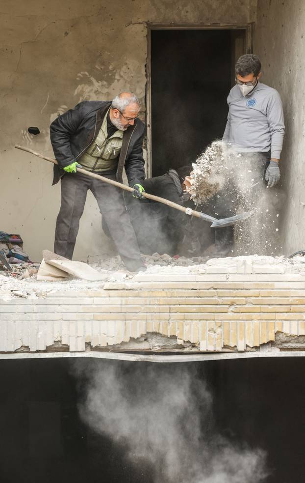 Men clear debris from an apartment damaged by an airstrike, in Tehran