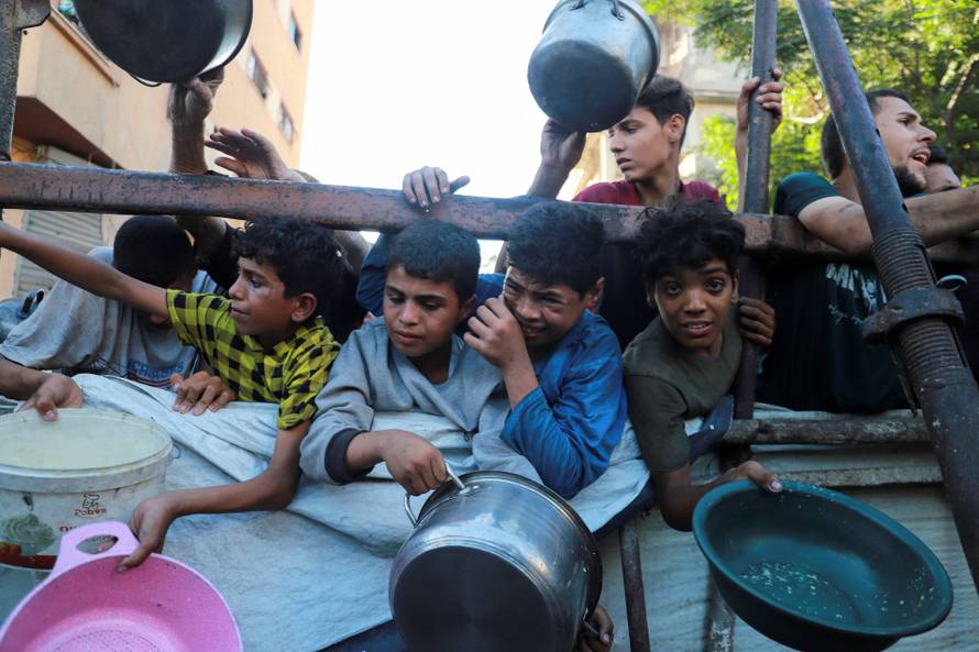 Palestinians gather to receive food from a charity kitchen amid hunger crisis, in Gaza City