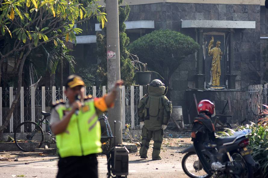 A member of the police bomb squad unit examines the site of an explosion outside the Immaculate Santa Maria Catholic Church, in Surabaya, East Java