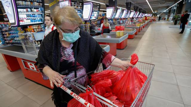 A woman wears a mask as she packs her groceries after the government limited the number of customers in supermarkets to 50 at a time due to coronavirus (COVID-19) threat in Podgorica
