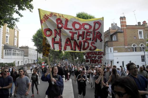 Demonstrators hold up banners during a march in Kensington, following the fire that destroyed The Grenfell Tower block, in north Kensington, West London