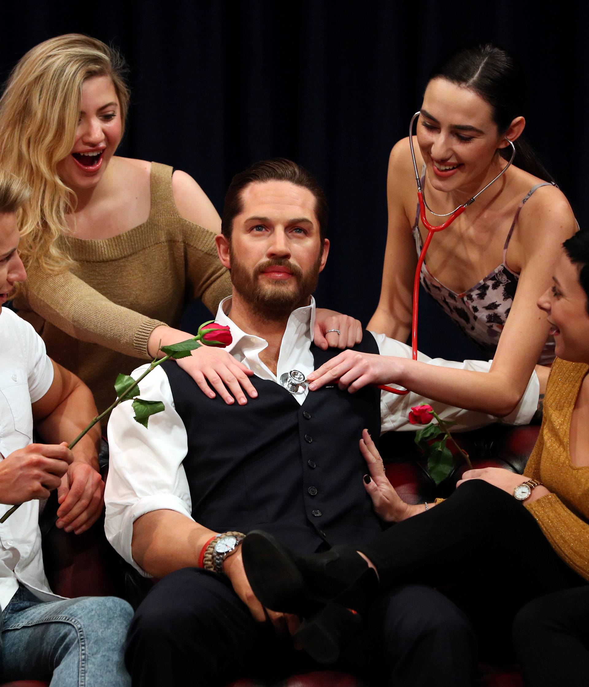 People pose next to Madame Tussauds' wax figure of British actor Tom Hardy which has a soft warm chest and a beating heart, in London