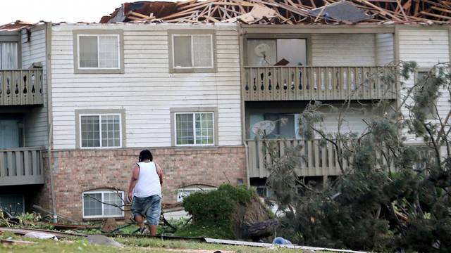 A man walks through the scattered debri outside his apartment building in the morning after a tornado touched down overnight in Trotwood