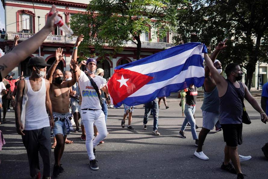 People hold Cuba's national flag during protests against and in support of the government, in Havana