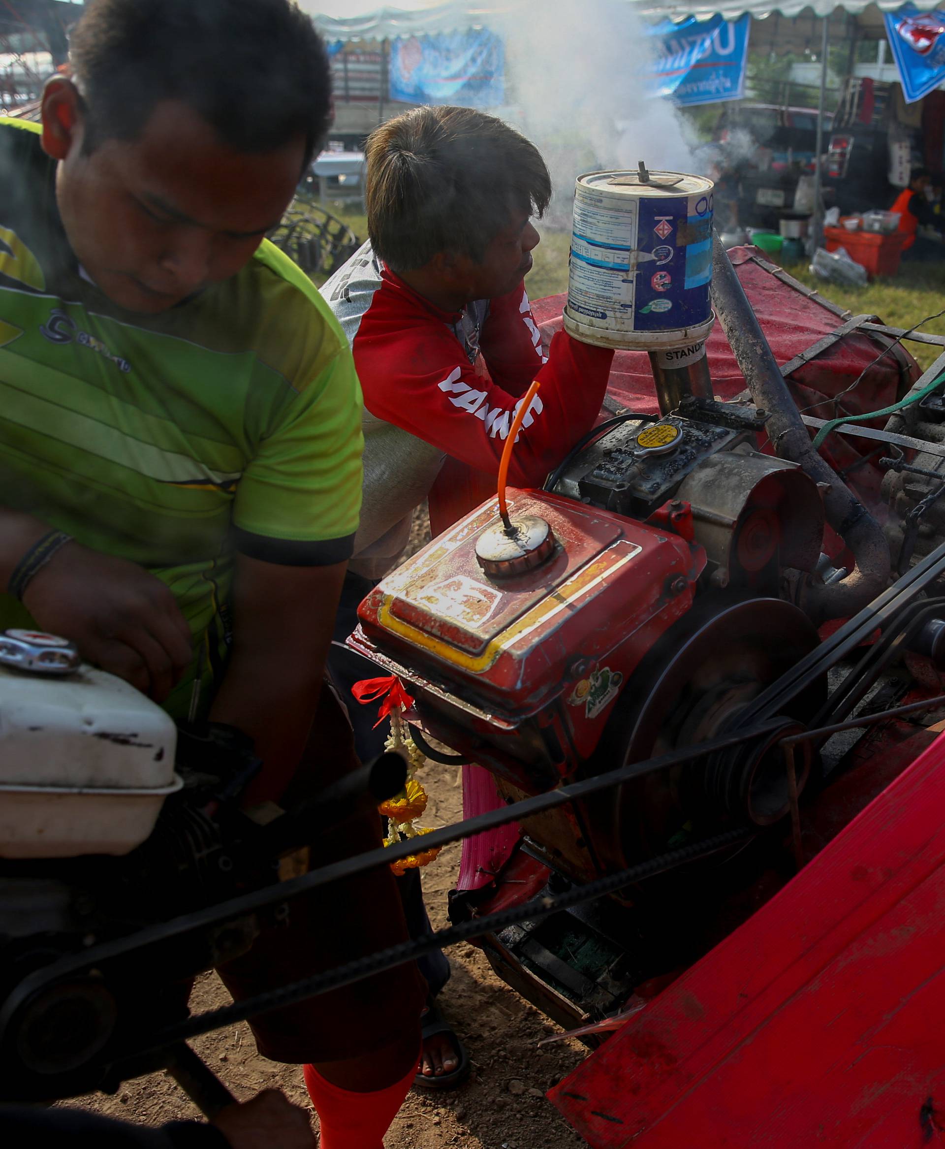 Team members work on an engine of modified tractor before a tractor race in Suphan Buri province