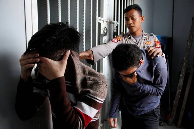 Two Indonesian men, who were later sentenced to 85 lashes of the cane for having sex together, are escorted by police into an Islamic court in Banda Aceh, Aceh province