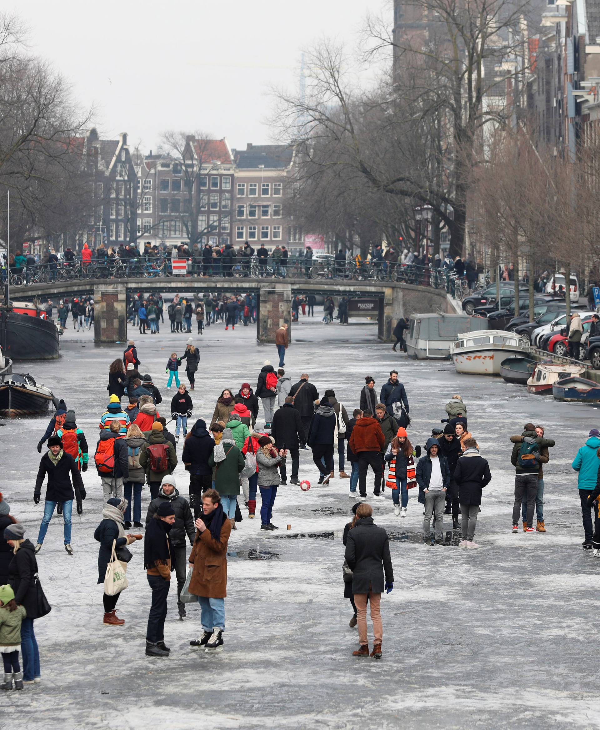 Ice skaters skate and walk on the frozen Prinsengracht canal during icy weather in Amsterdam