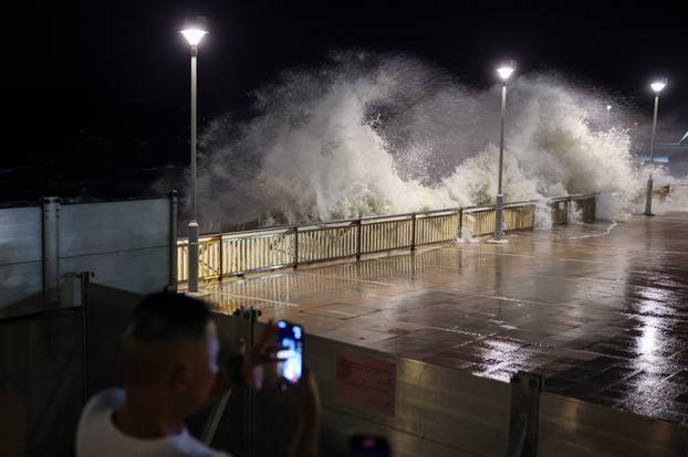 A resident takes photos of rough waves from the shore before Super Typhoon Ragasa makes its closest approach to Hong Kong