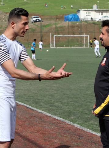 Biwar Abdullah, 25, an Iraqi Kurdish local footballer, who looks like the football player Cristiano Ronaldo, speaks with his local coach at a football yard in the district of Soran, northeast of Erbil