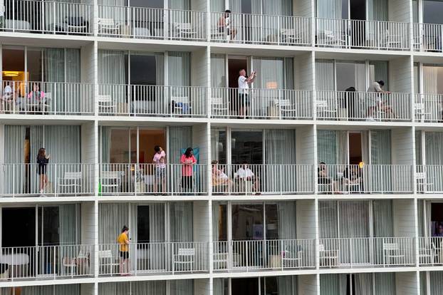 Vacationers stand on balconies at the 'Alohilani Resort looking towards Waikiki Beach after authorities warned of the possibility of tsunami waves