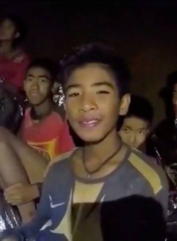 Boys from the under-16 soccer team trapped inside Tham Luang cave covered in hypothermia blankets react to the camera in Chiang Rai, Thailand