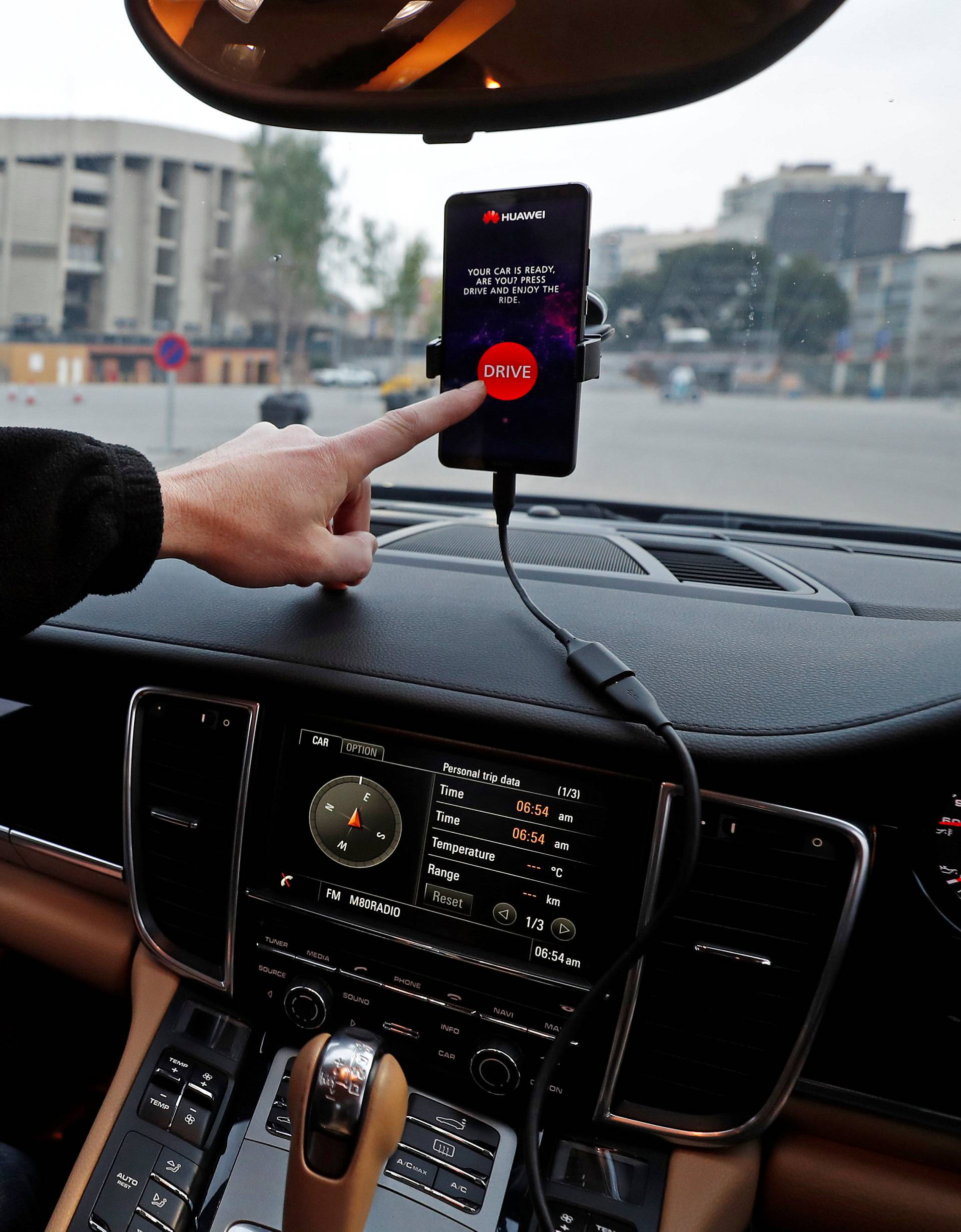 An engineer points to a Huawei Mate 10 Pro mobile used to control a driverless car during the Mobile World Congress in Barcelona