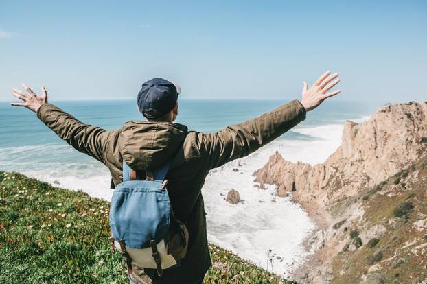 A Tourist with a backpack shows how he is free and happy.