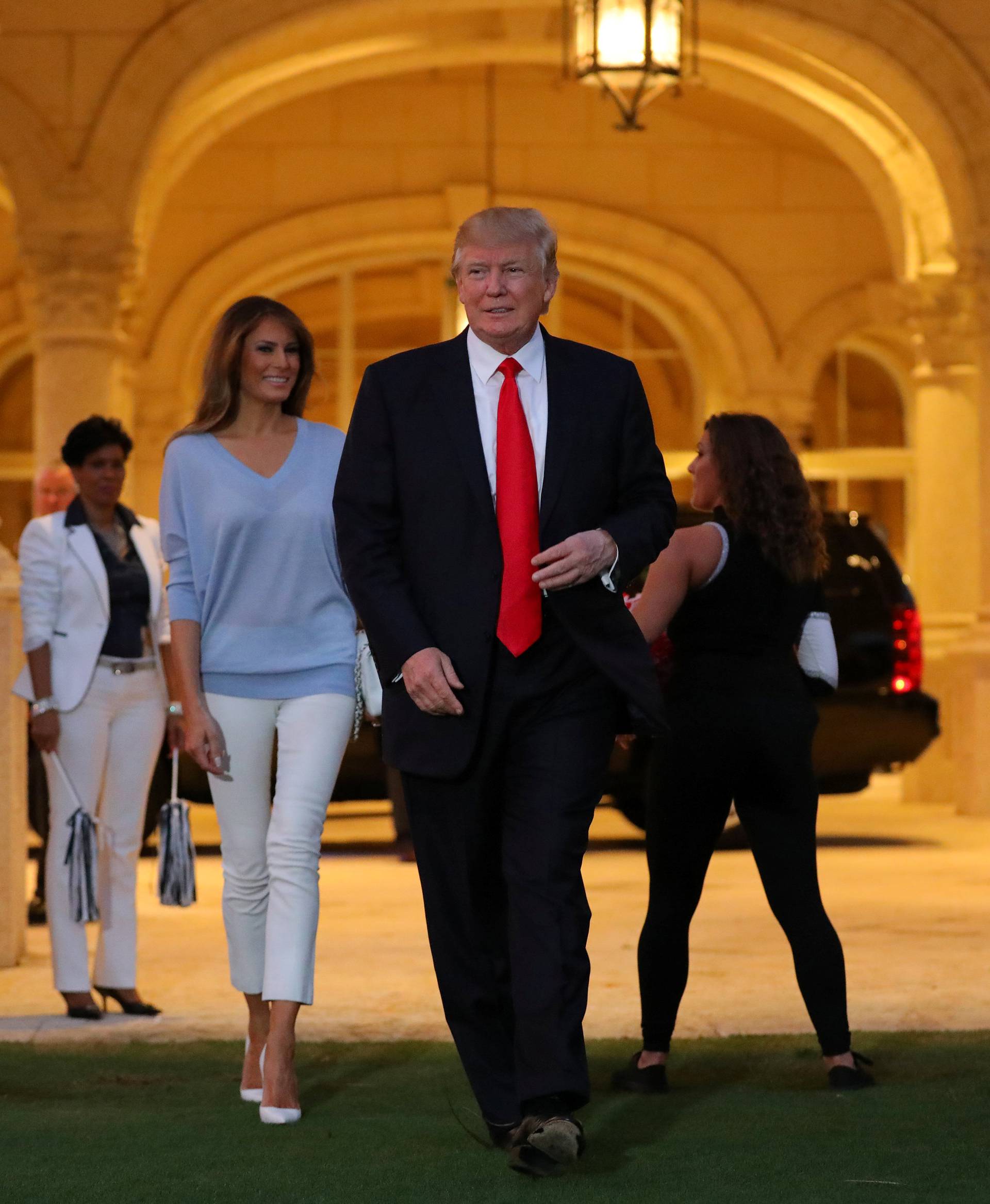 U.S. President Donald Trump and First Lady Melania Trump greet a marching band as they arrive at Trump International Golf club to watch the Super Bowl LI between New England Patriots and Atlanta Falcons in West Palm Beach, Florida, U.S.