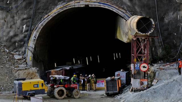 Members of rescue teams stand at the entrance of a tunnel where road workers are trapped after a portion of the tunnel collapsed in Uttarkashi