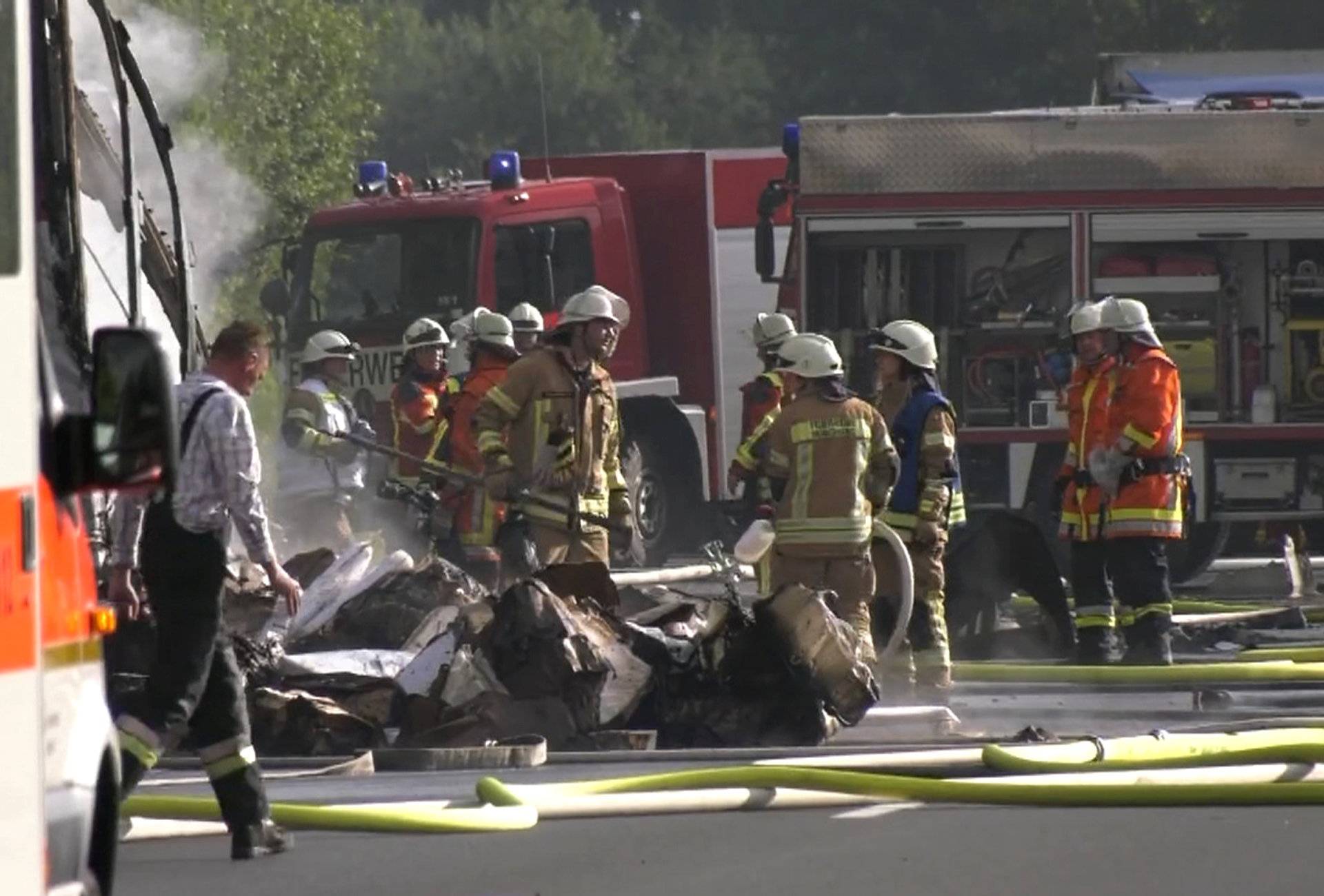 Firefighters are seen at the site where a coach burst into flames after colliding with a lorry on a motorway near Muenchberg