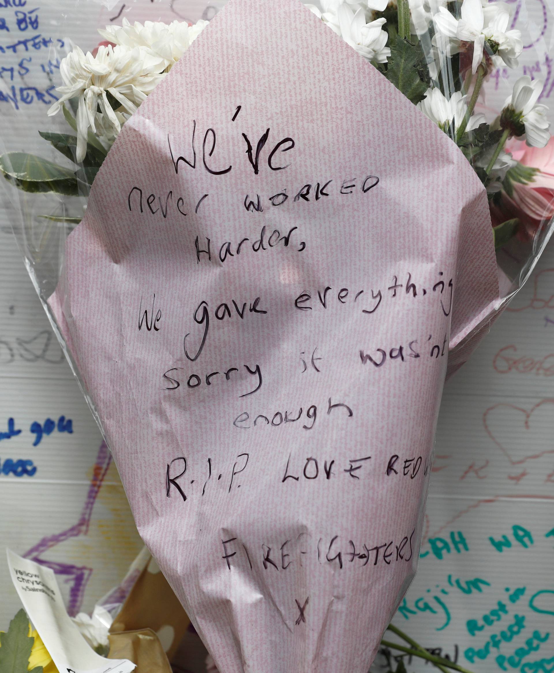 Floral tributes, one bearing a message from the London Fire Brigade are placed near The Grenfell Tower block, which was destroyed by fire, in north Kensington, West London
