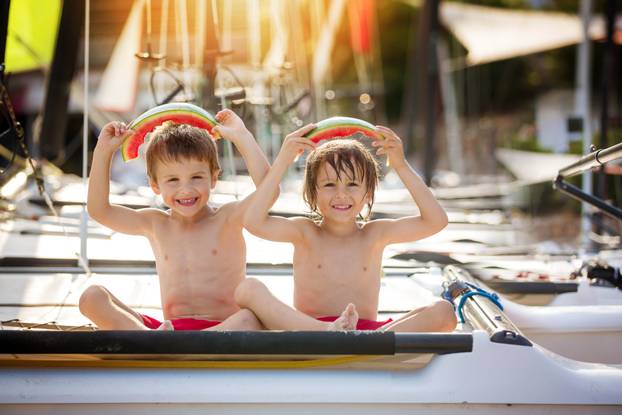 Two little children, boy brothers, eating watermelon on the beac