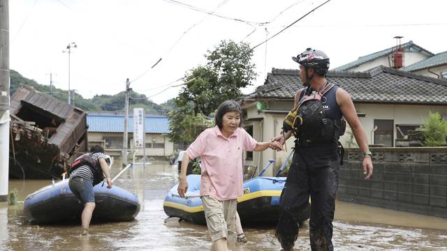 A rescue worker helps local residents at a flooded area caused by a heavy rain along Kuma River in Hitoyoshi, Japan
