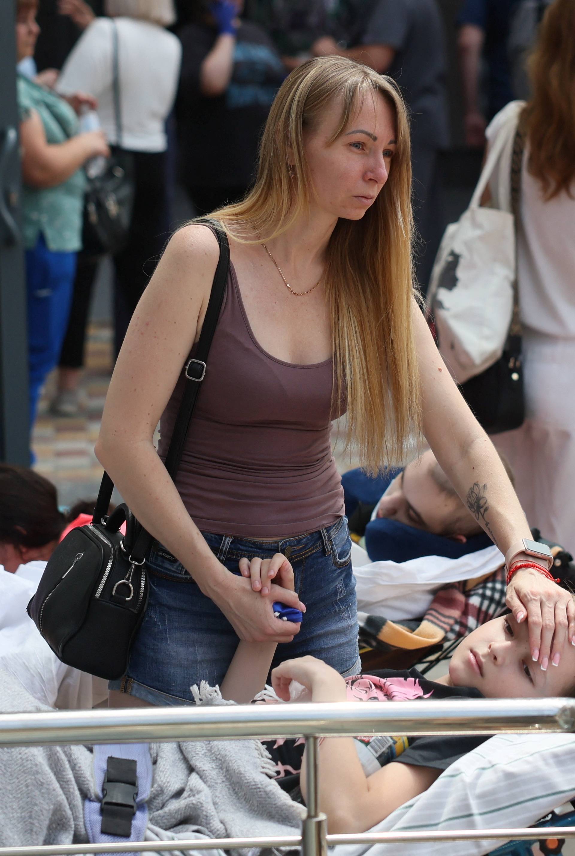 A woman touches a patient near Ohmatdyt Children's Hospital that was damaged during Russian missile strikes, in Kyiv