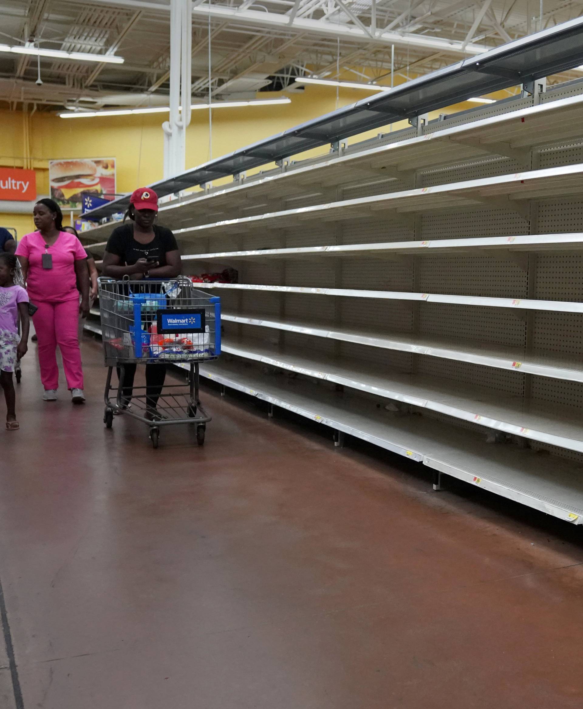 People walk past empty shelves where bread is normally sold in a Walmart store in advance of Hurricane Irma's expected arrival in North Miami Beach