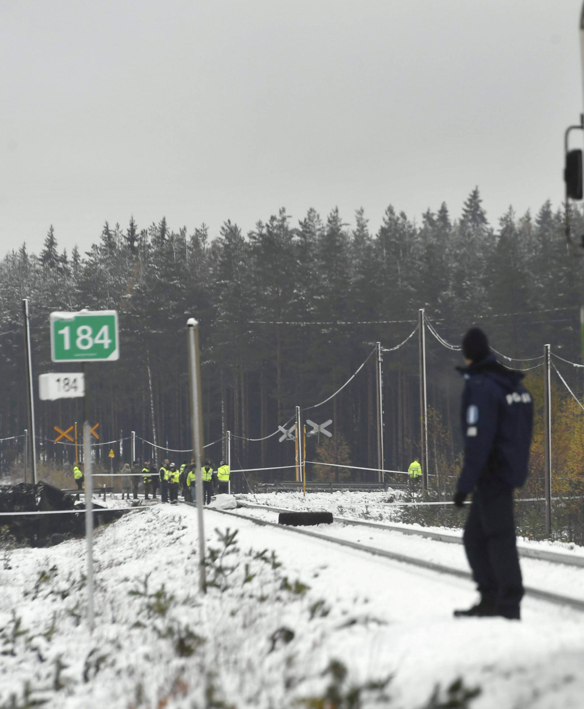 Rescue and military personnel and a policeman are seen at the railroad crossing after a crash between a train and a military truck in Raasepori