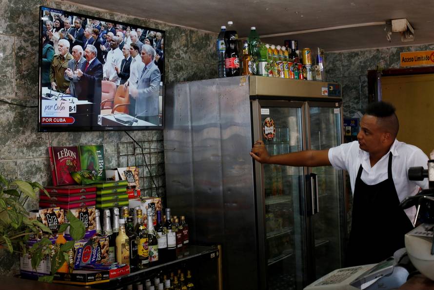 Cuba's President Raul Castro and  First Vice-President Miguel Diaz-Canel are seen on a TV screen inside a restaurant during a session of the National Assembly in Havana