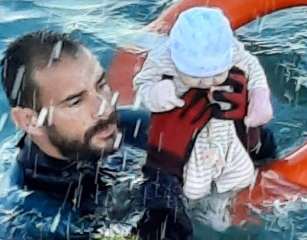 A member of the Spanish Guardia Civil holding a migrant baby in the water off the shore of the Spanish enclave of Ceuta is seen in this handout picture