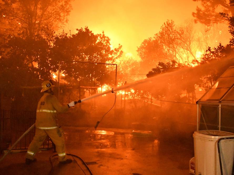 A firefighter battles a wind-driven wildfire called the Saddle Ridge fire in the early morning hours Friday in Porter Ranch