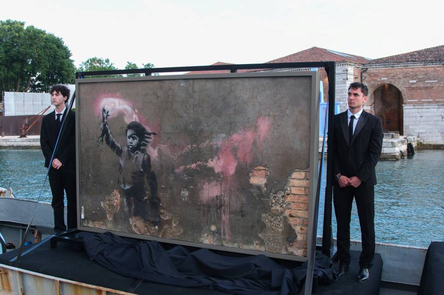 Newly restored mural attributed to Banksy depicting a migrant child wearing a lifejacket and holding a pink flare is presented in Venice
