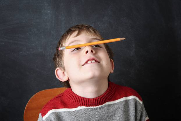 Young,Bored,Boy,Balancing,A,Pencil,On,His,Nose.