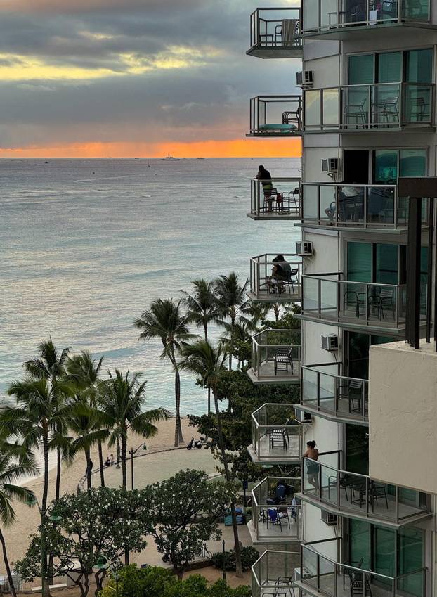 Vacationers stand on balconies at the Aston Waikiki Circle Hotel looking towards Waikiki Beach after authorities warned of the possibility of tsunami waves