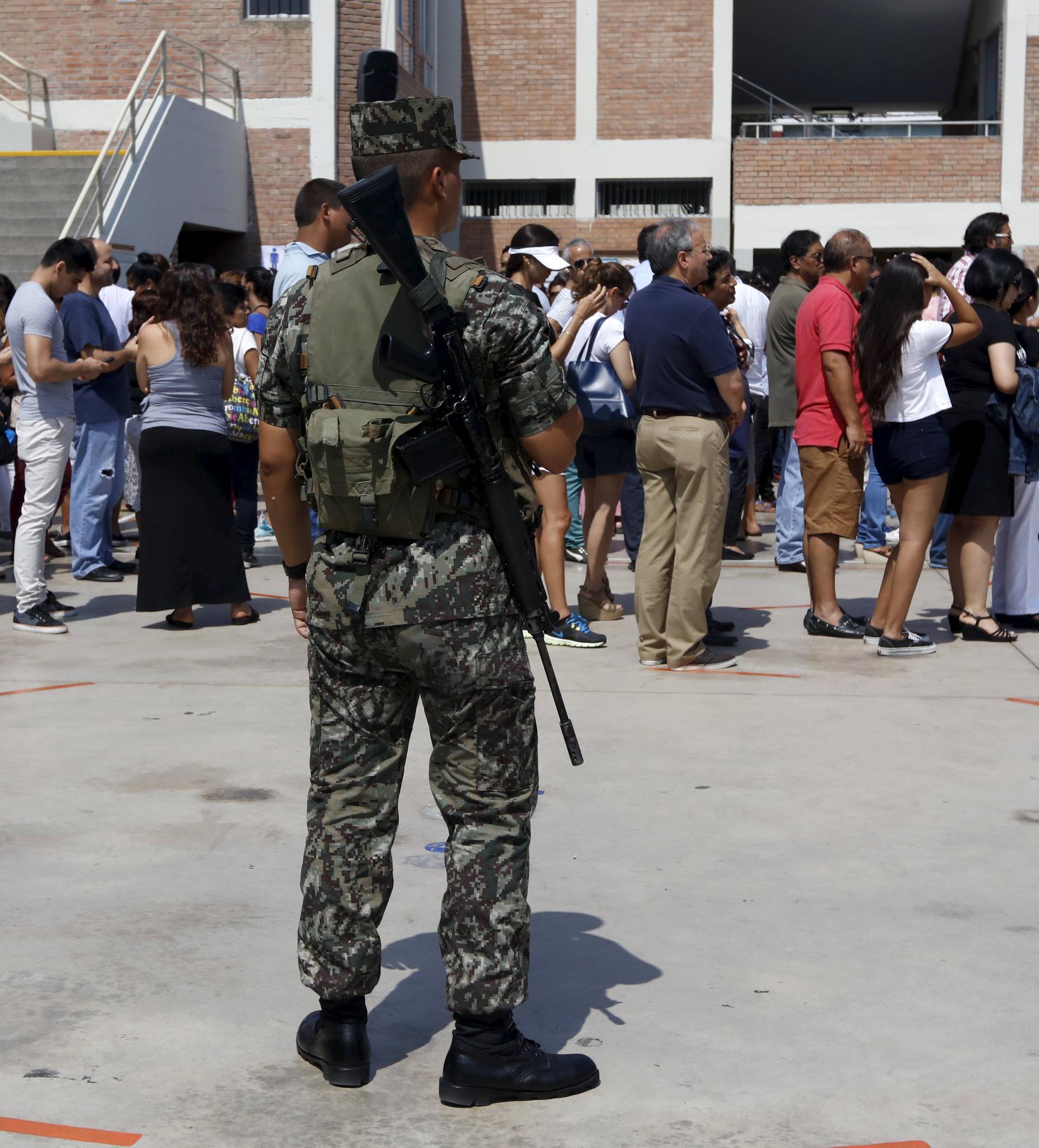 A soldier guards as people line up to vote during presidential election at a polling station in Lima's district of San Isidro