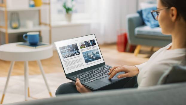 Young,Woman,At,Home,Is,Using,Laptop,Computer,For,Scrolling