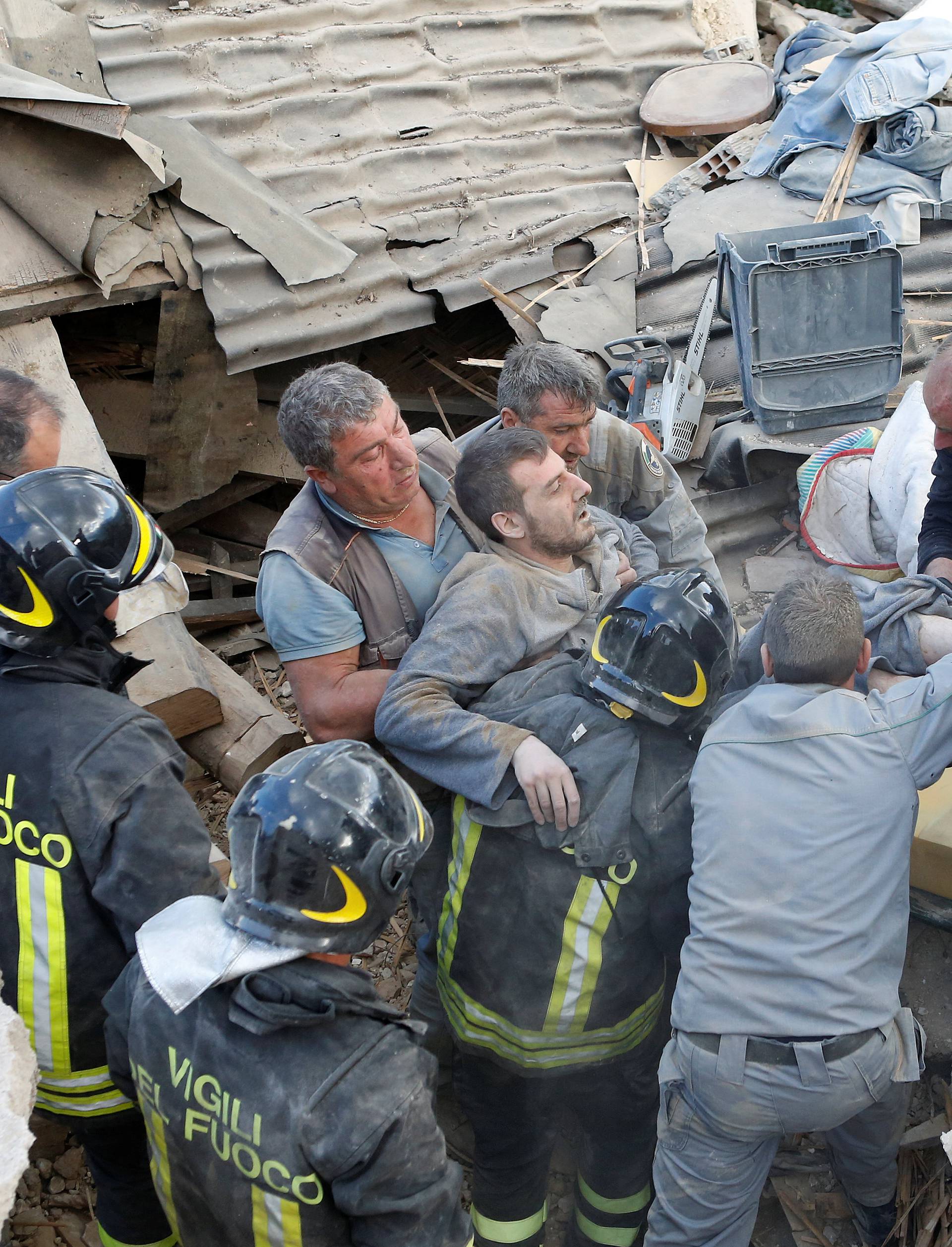 A man is carried away after having been rescued alive from the ruins following an earthquake in Amatrice