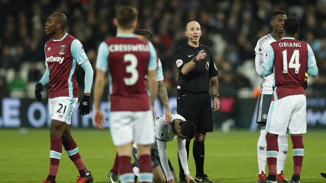 Referee Mike Dean gestures after awarding Manchester United a free kick for a foul on Henrikh Mkhitaryan