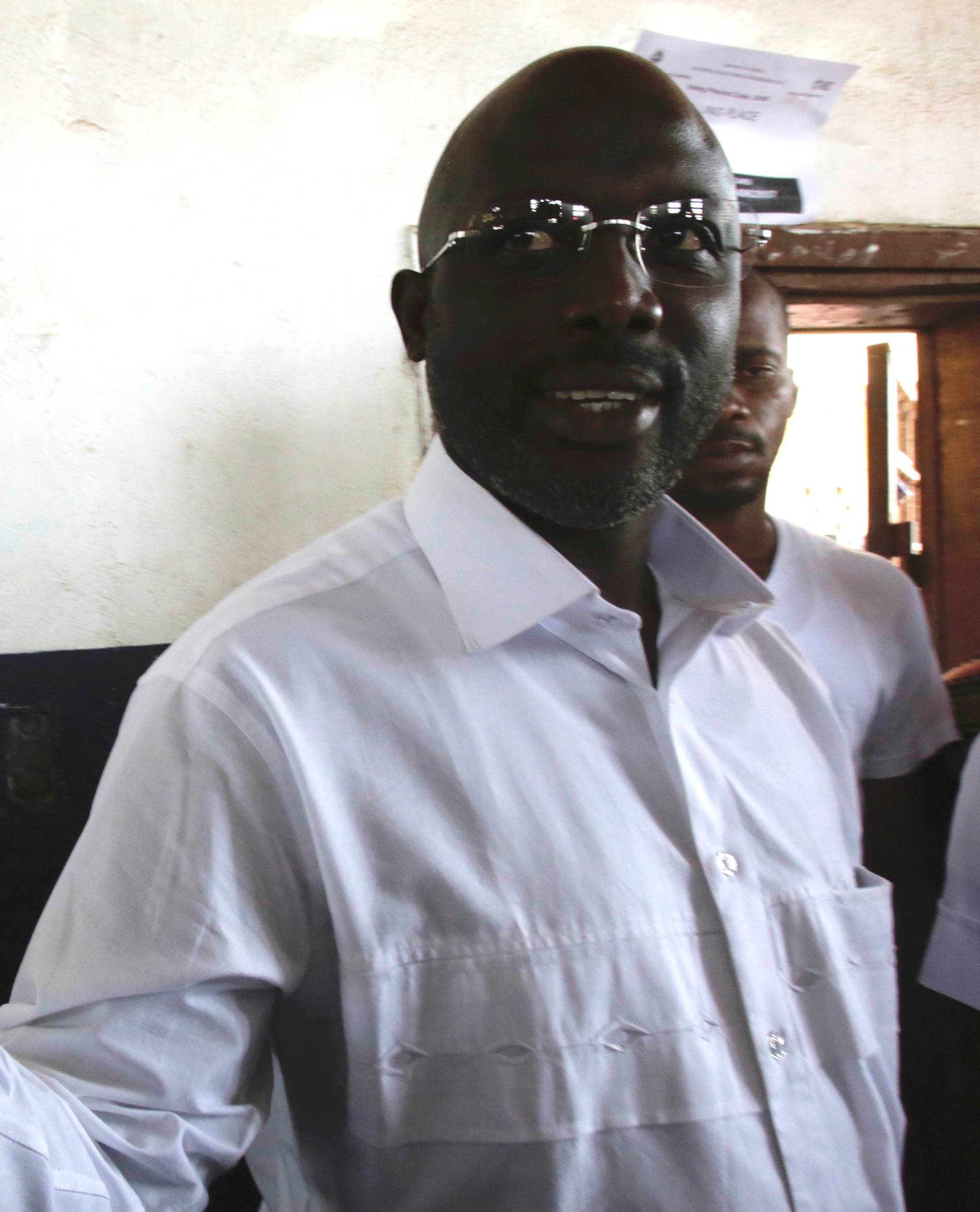 Weah, former soccer player and presidential candidate of CDC shows his voter's card in Monrovia
