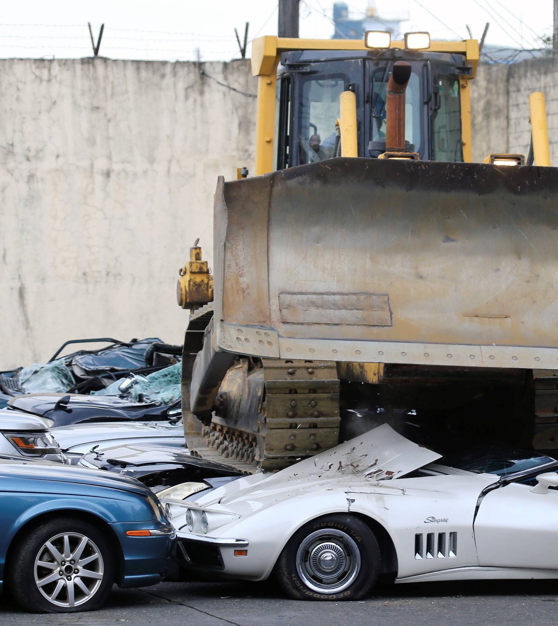 A bulldozer destroys condemned smuggled luxury cars worth 61,626,000.00 pesos during the 116th Bureau of Customs founding anniversary in Manila